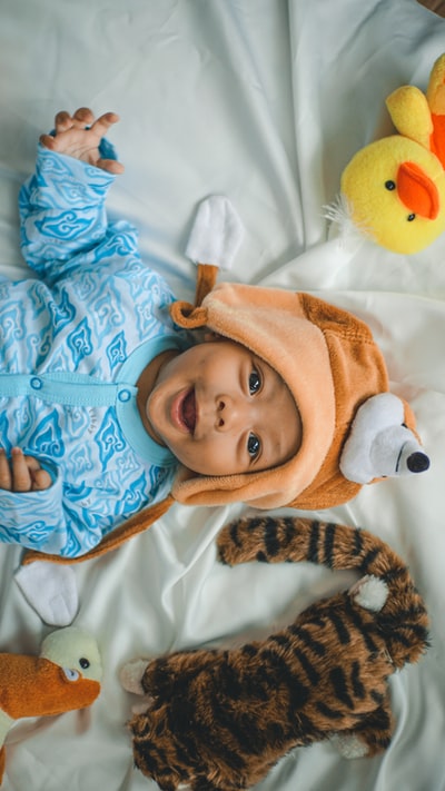 Baby dressed in blue and white jacket zipper lying on the white fabric
